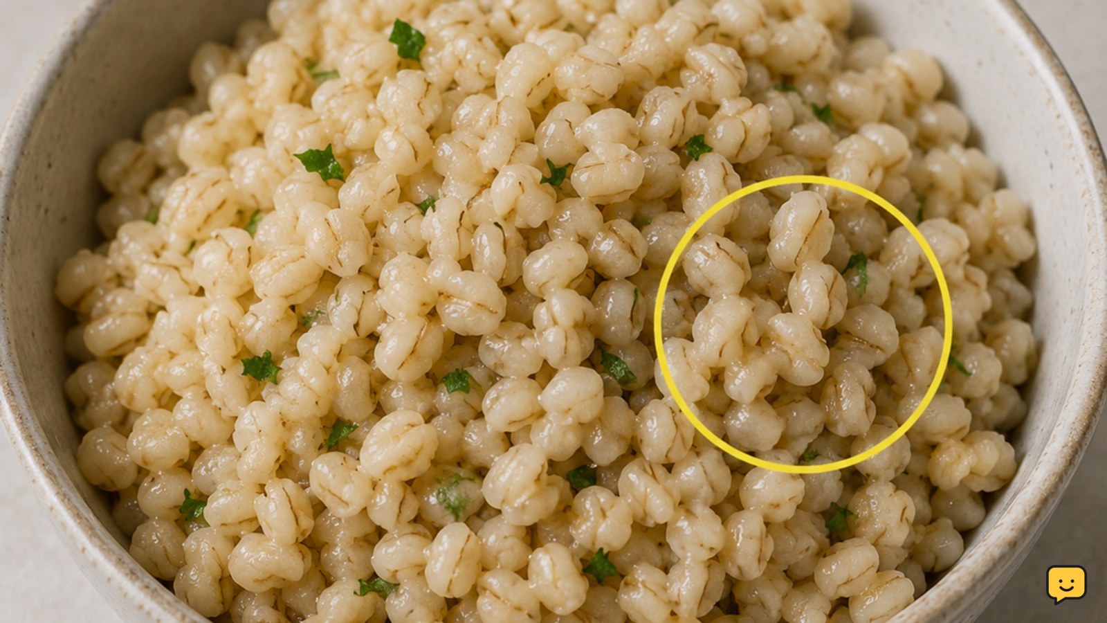Bowl of cooked barley with plump chewy grains and herbs