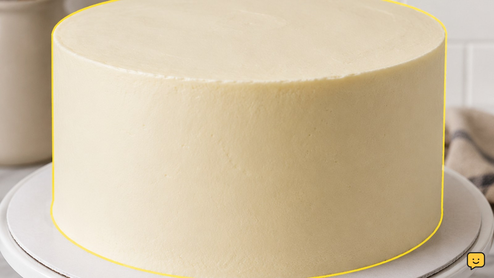Layered cake covered with smooth buttercream frosting on a cake stand