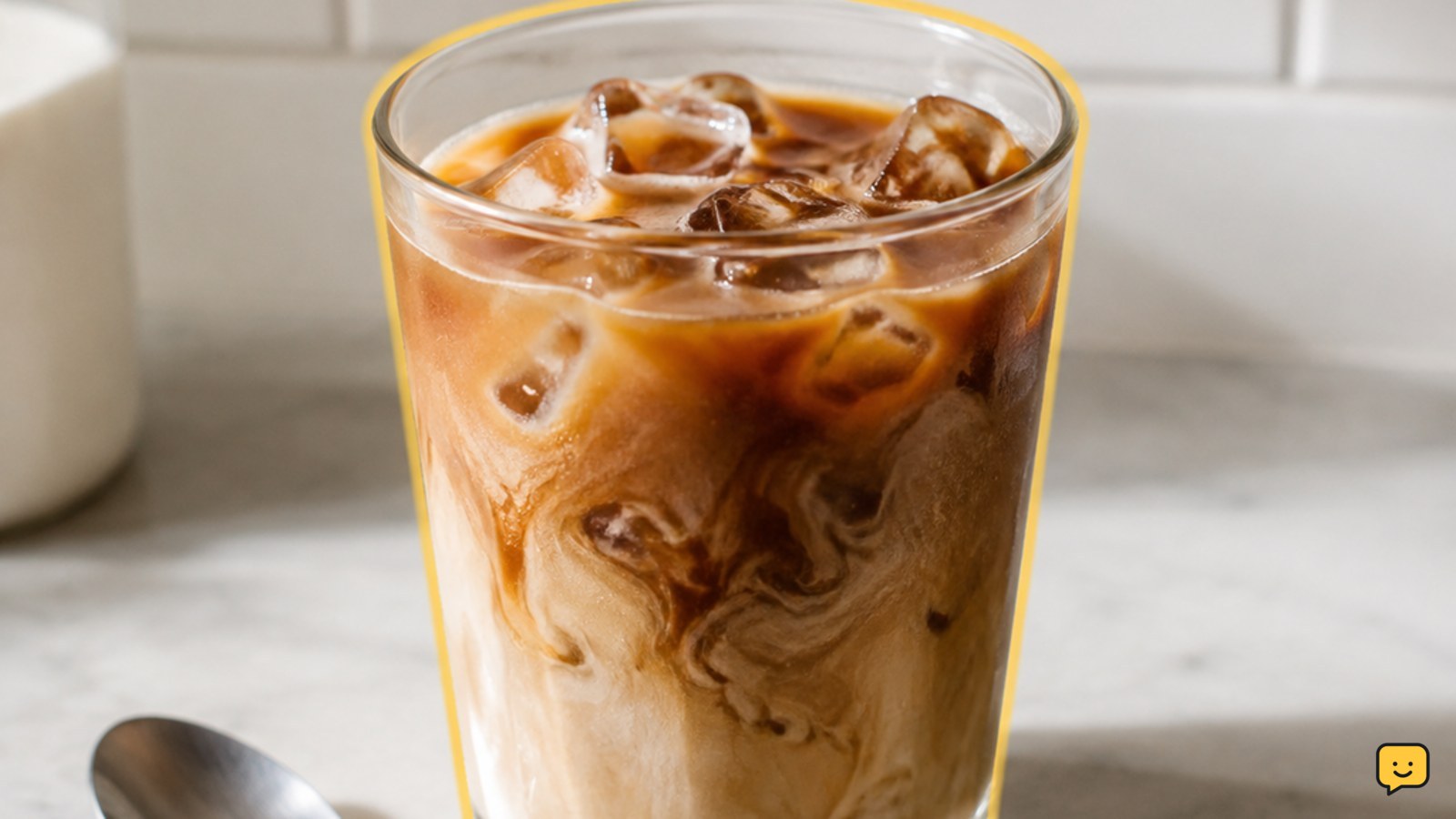 Glass of iced coffee filled with ice and lightly mixed with milk