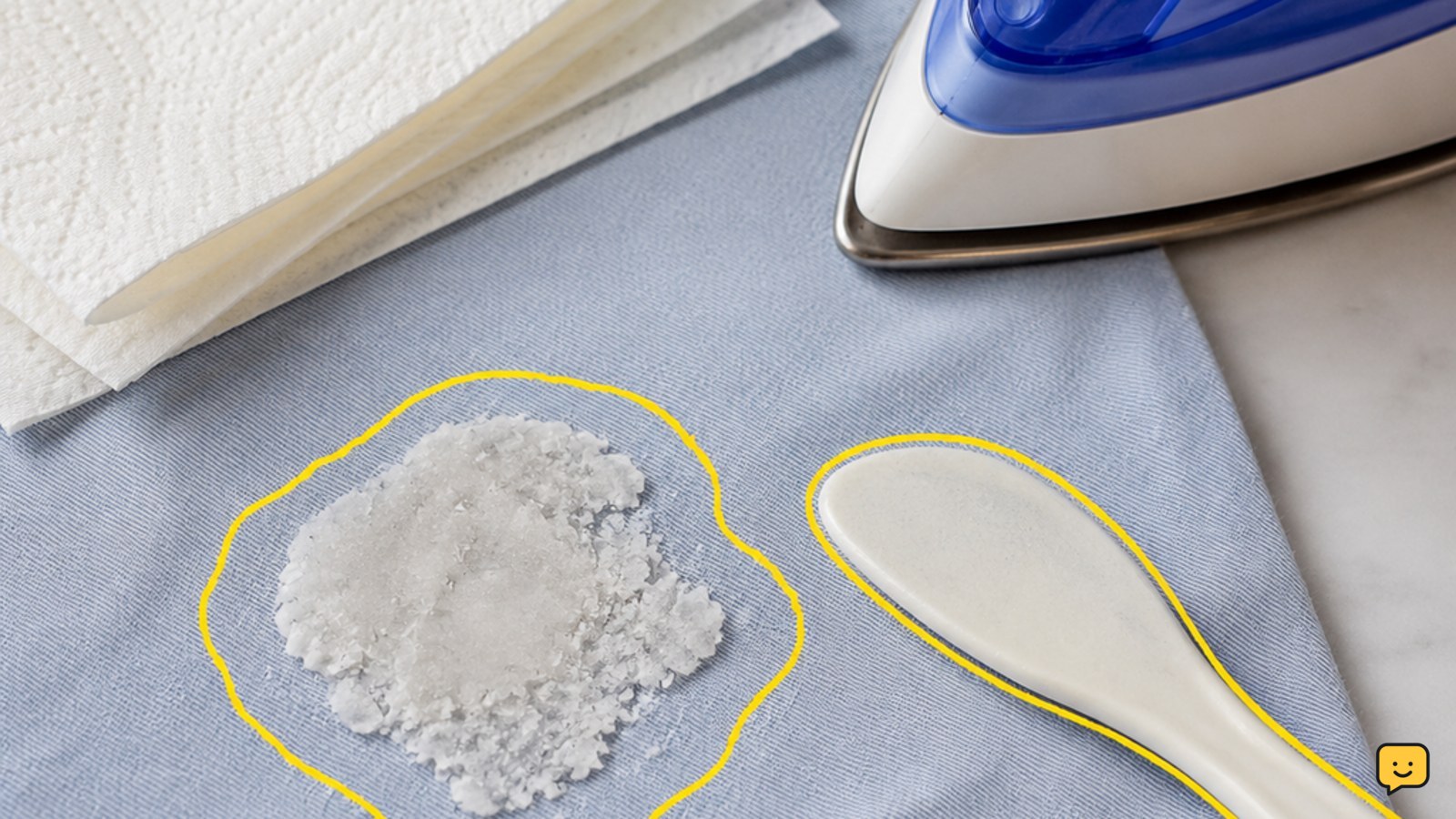 Hardened candle wax on washable fabric beside a dull scraper, white paper towels, and an iron