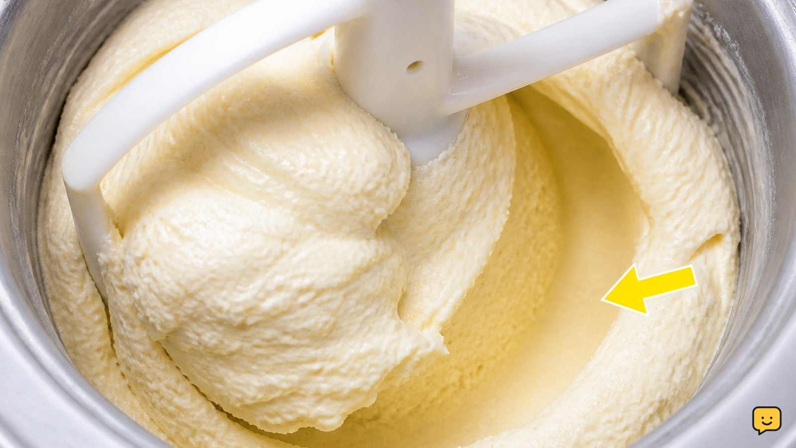 Freshly churned vanilla ice cream with a visible dasher track and soft-serve consistency inside an ice cream maker bowl